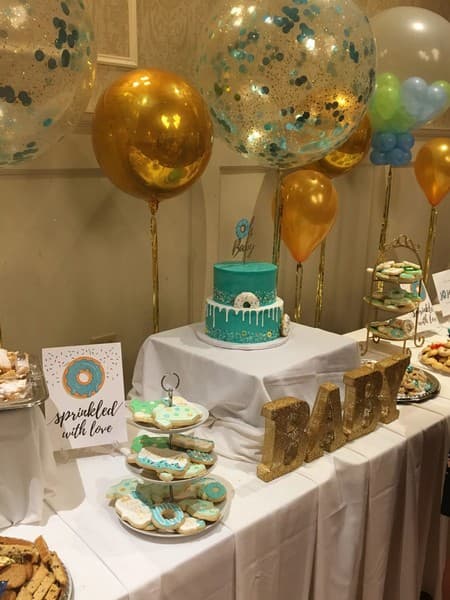 Full table setup with balloons cake and loads of treats green and gold themed